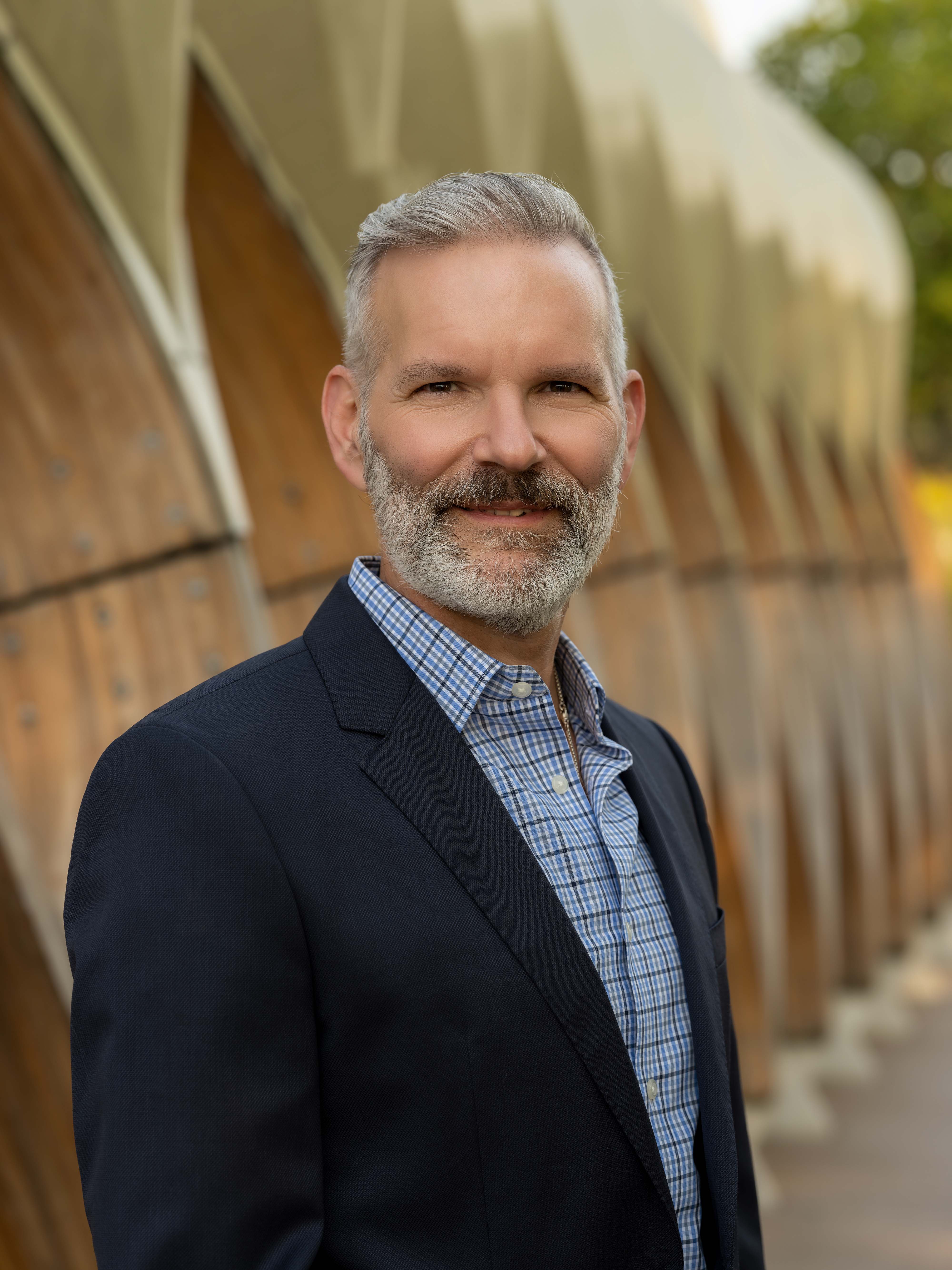 Executive headshot outdoors, navy suit and check shirt