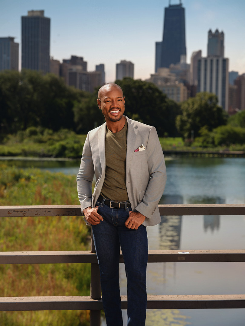 Man in a grey blazer on a bridge with the Chicago skyline behind him
