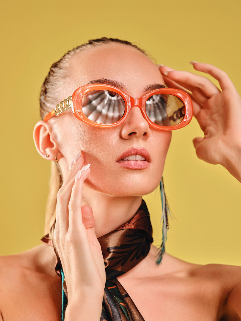 Woman in orange sunglasses on a yellow backdrop