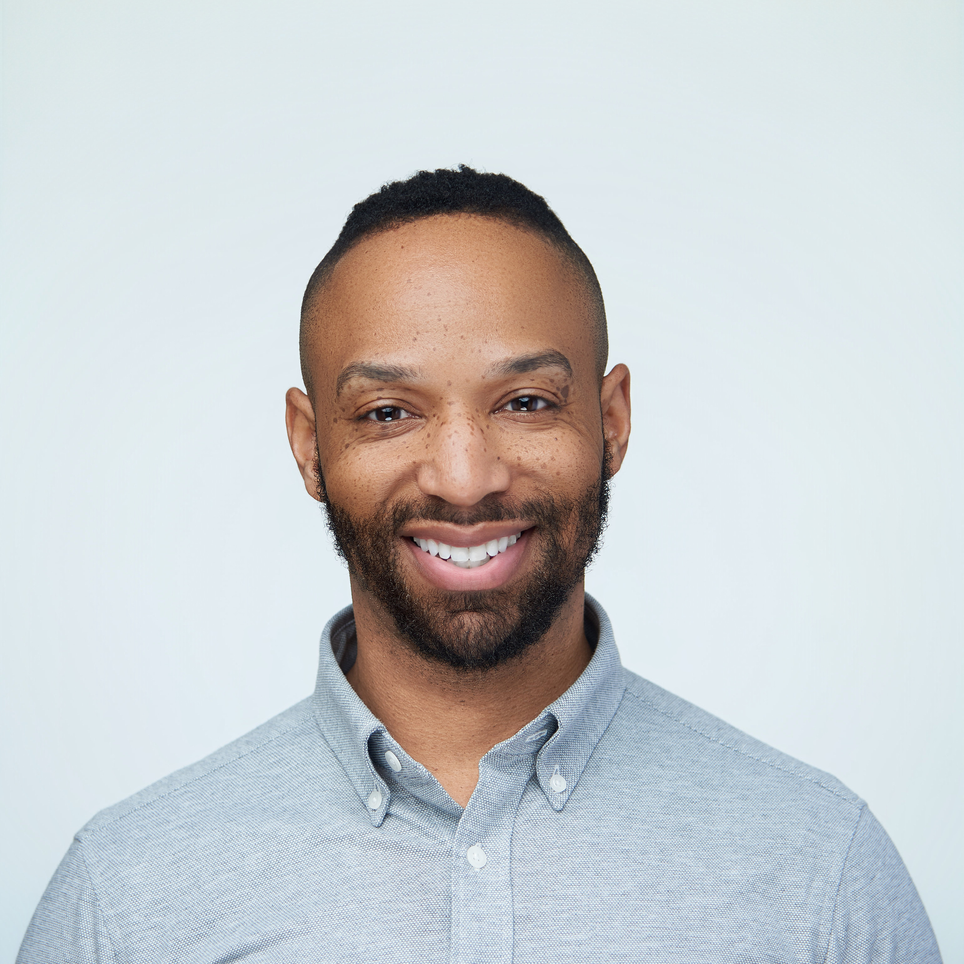 Man in a light blue shirt and blazer on a pale backdrop