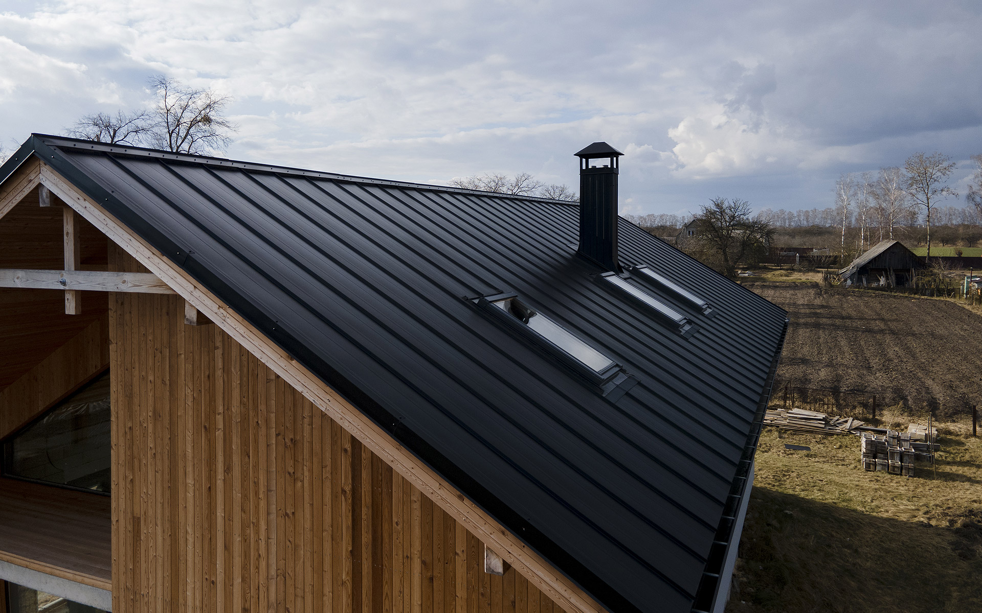 Metal standing seam roof installation on a modern house with skylights, providing sleek and weather-resistant protection