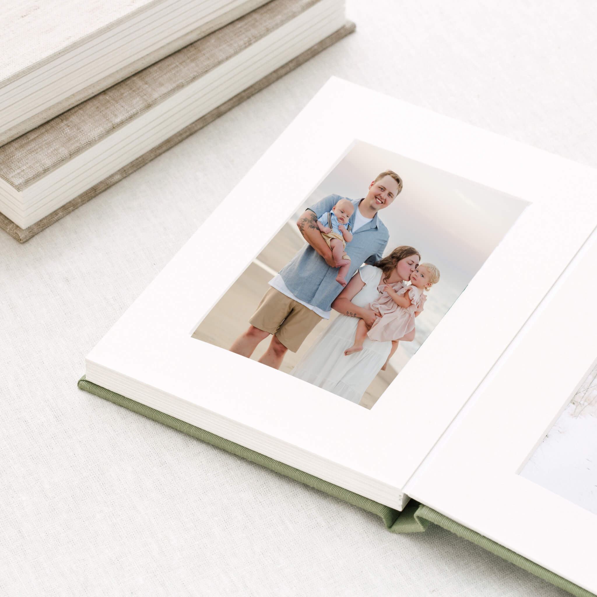 An example of heirloom matted albums. The album is open to a page, displaying a beach family photo.