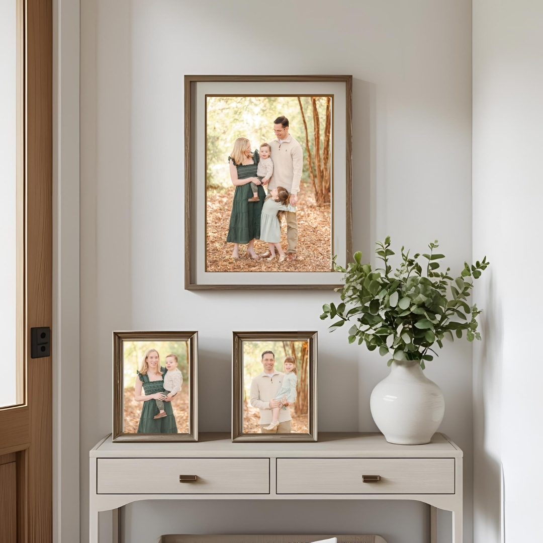 A mockup of two small framed photos on an entry table with one larger framed photo hanging on the wall above. All photos feature images from a fall family session.