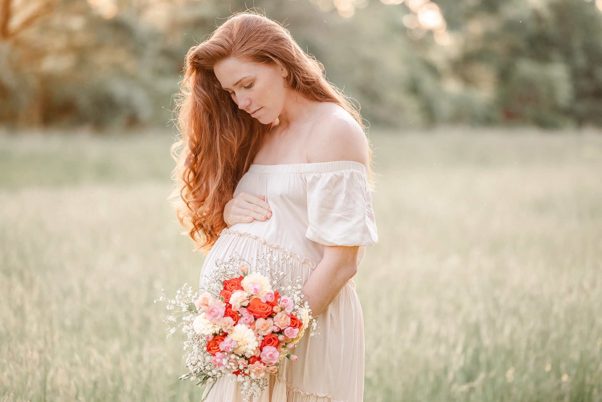 An expectant mother stands in a field during her maternity session with Chesapeake photographer, Justine Renee Photography. She is wearing a flowy beige dress and holding a colorful bouquet.
