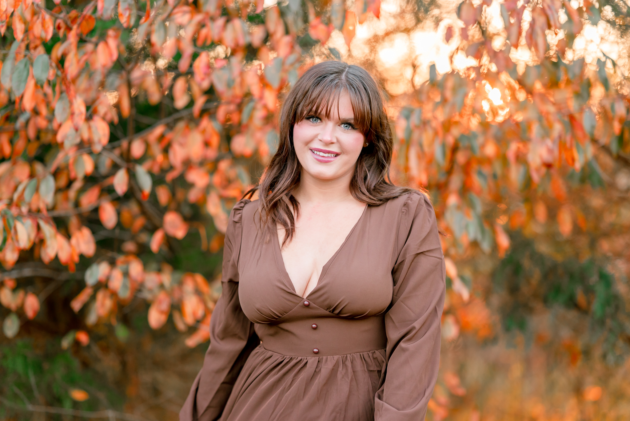 A high school senior stands in front of some fall foliage at Bells Mill Park in Chesapeake. Her brown dress compliments the fall leaves. A high school senior stands in front of some fall foliage at Bells Mill Park in Chesapeake. Her brown dress compliments the fall leaves.