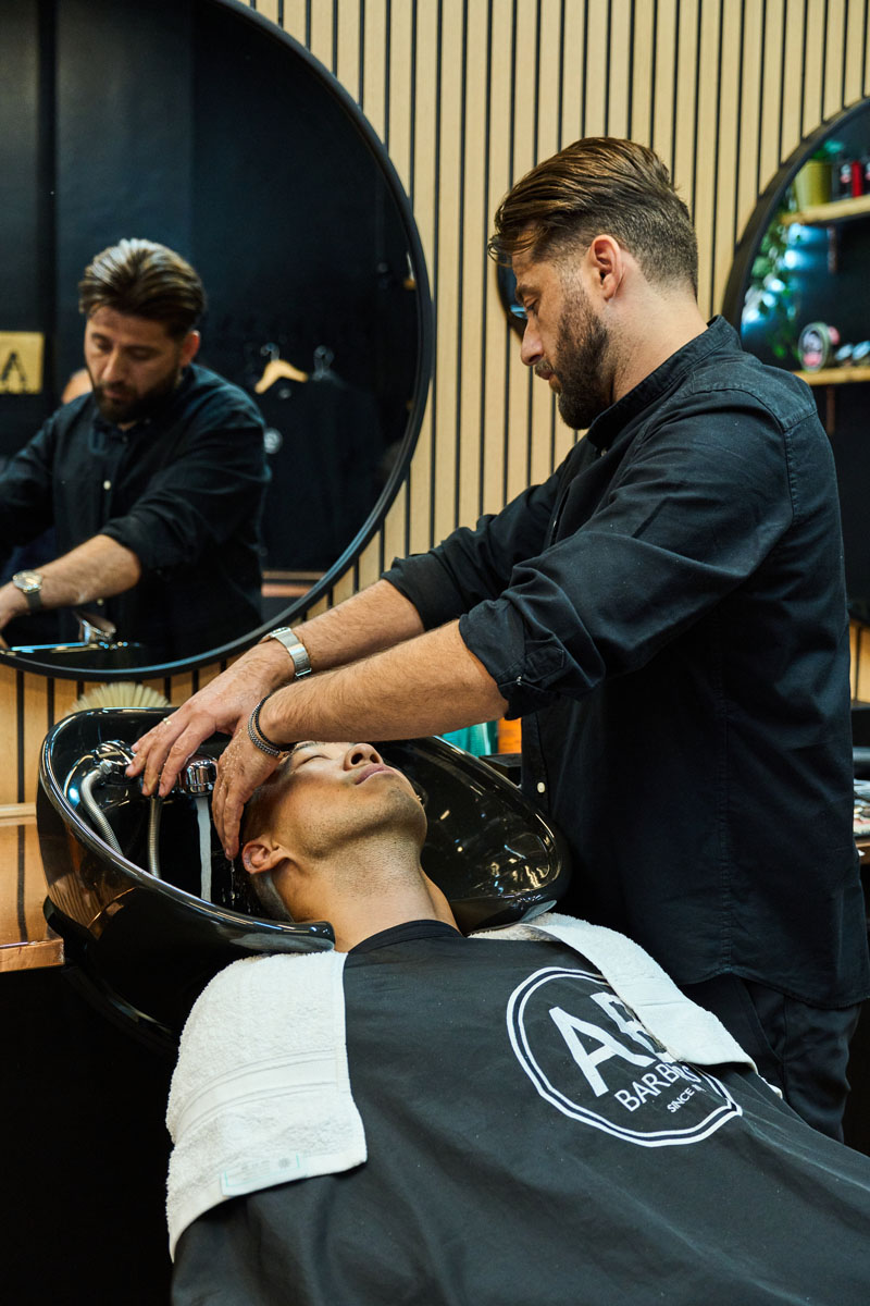 Man getting hair washed in sink at barbershop