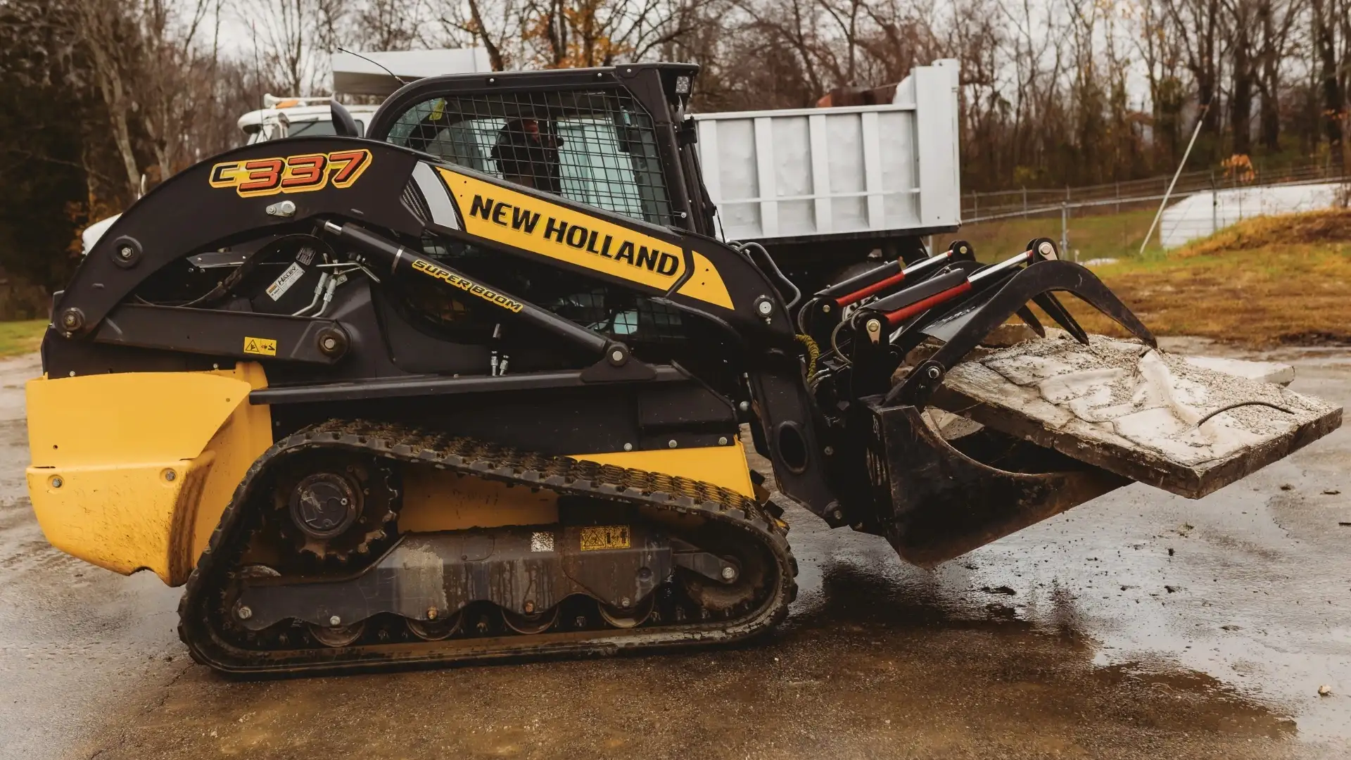 New Holland compact track loader with attachment on soft ground