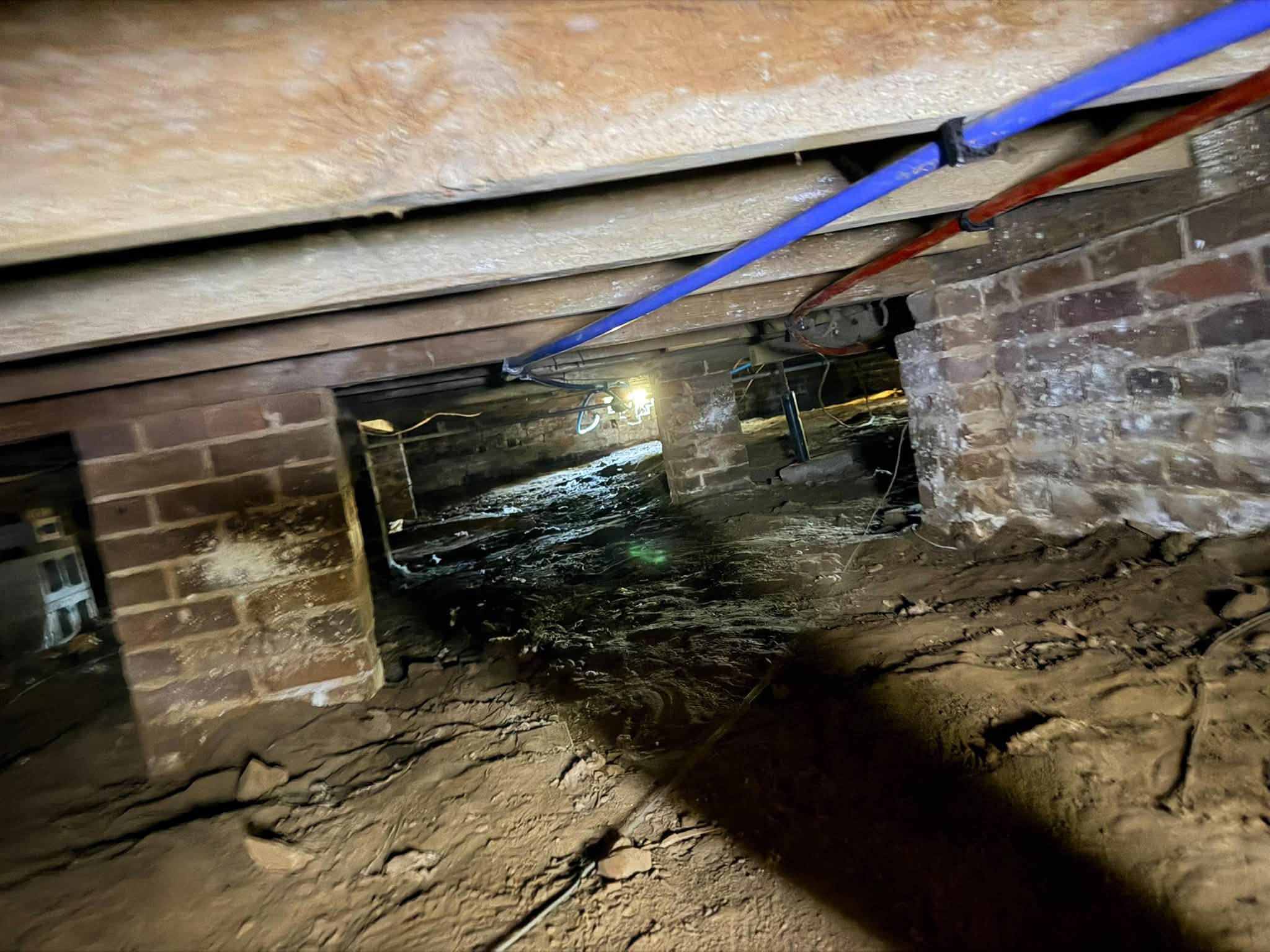 Crawlspace conditions under Pontotoc MS home — brick piers, spray foam insulation, and plumbing before new ductwork installation