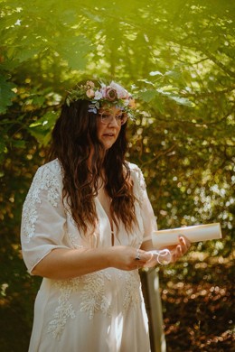 Woman in a flower crown reading her handfasting vows in woodland
