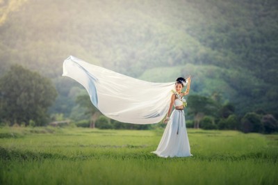 Woman in a white dress with fabric lifted by the wind, representing the Air element Woman in a white dress with fabric lifted by the wind, representing the Air element