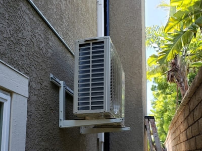 Wall-mounted mini-split air conditioning unit installed on the exterior of a residential home in Irvine, designed for energy-efficient cooling in tight spaces.