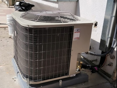 Outdoor residential air conditioning unit in need of maintenance, located on the side of a home, with focus on improving cooling performance.