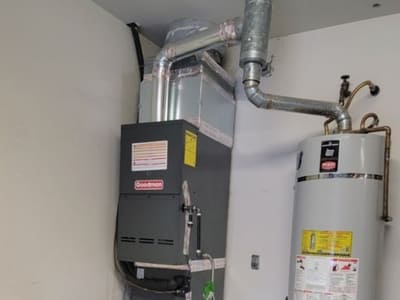 Goodman HVAC system installed alongside a water heater in a residential garage, providing reliable heating for the home.