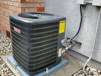 Goodman outdoor residential air conditioning unit installed next to a brick wall, providing cooling for the home.