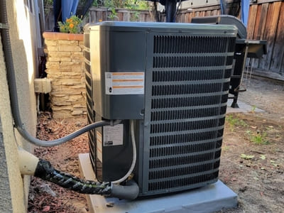 Residential outdoor air conditioning unit installed beside a house, designed for efficient cooling and energy-saving performance.