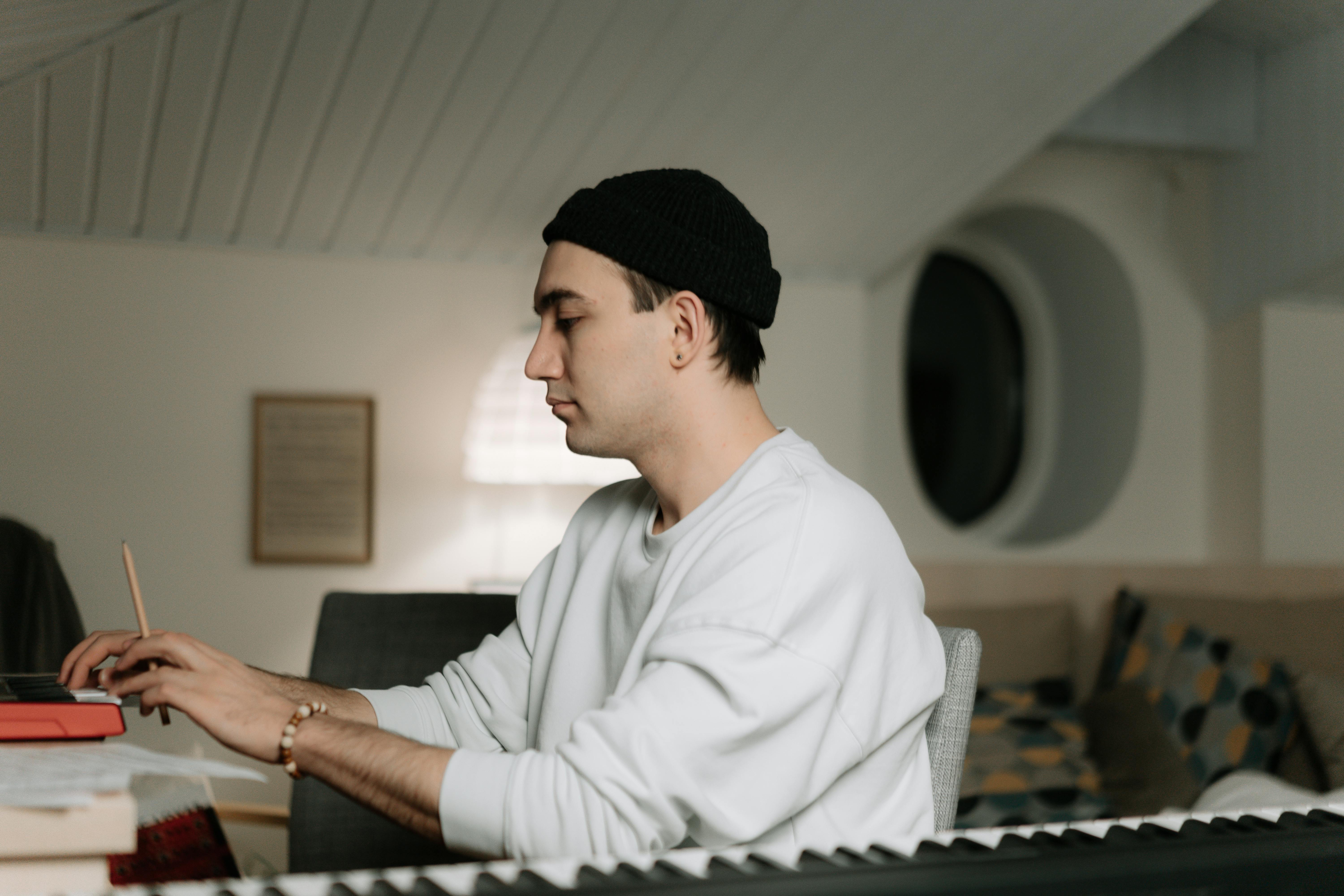 Man holding pencil writing music at keyboard Man holding pencil writing music at keyboard