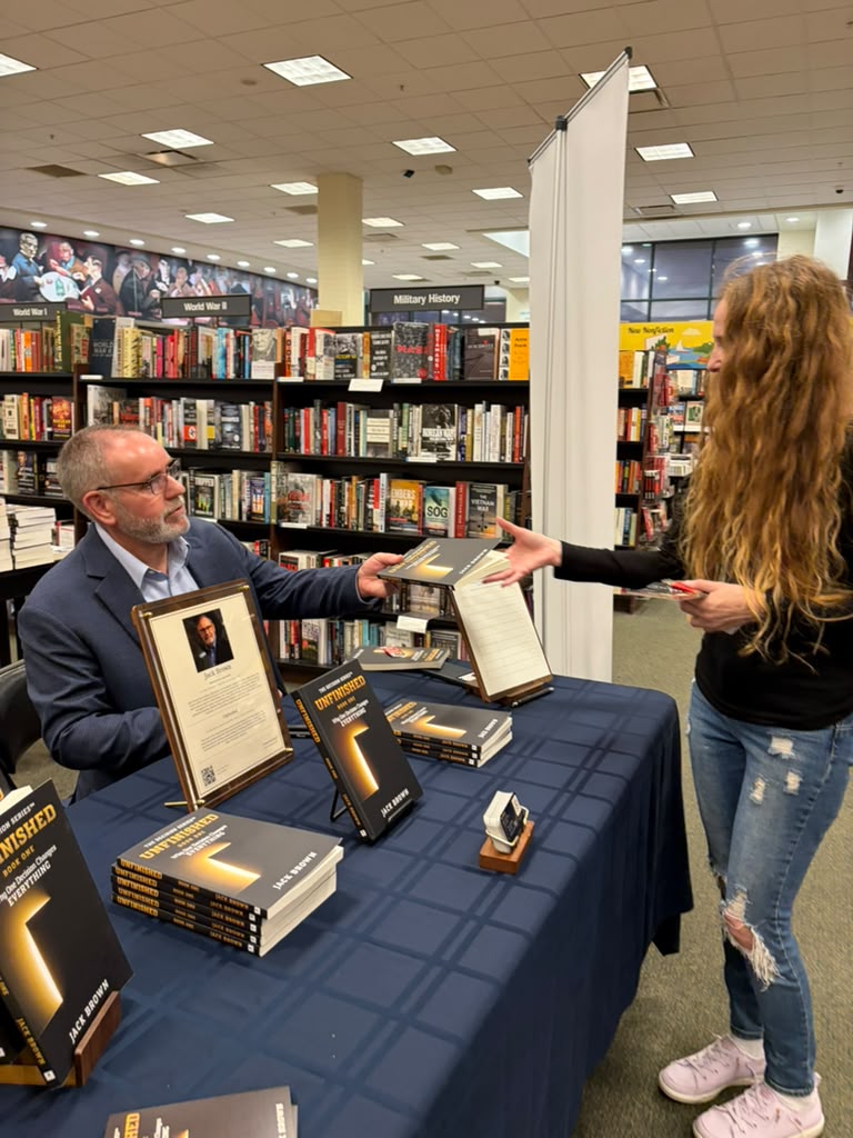 Jack Brown handing a copy of Unfinished to a reader