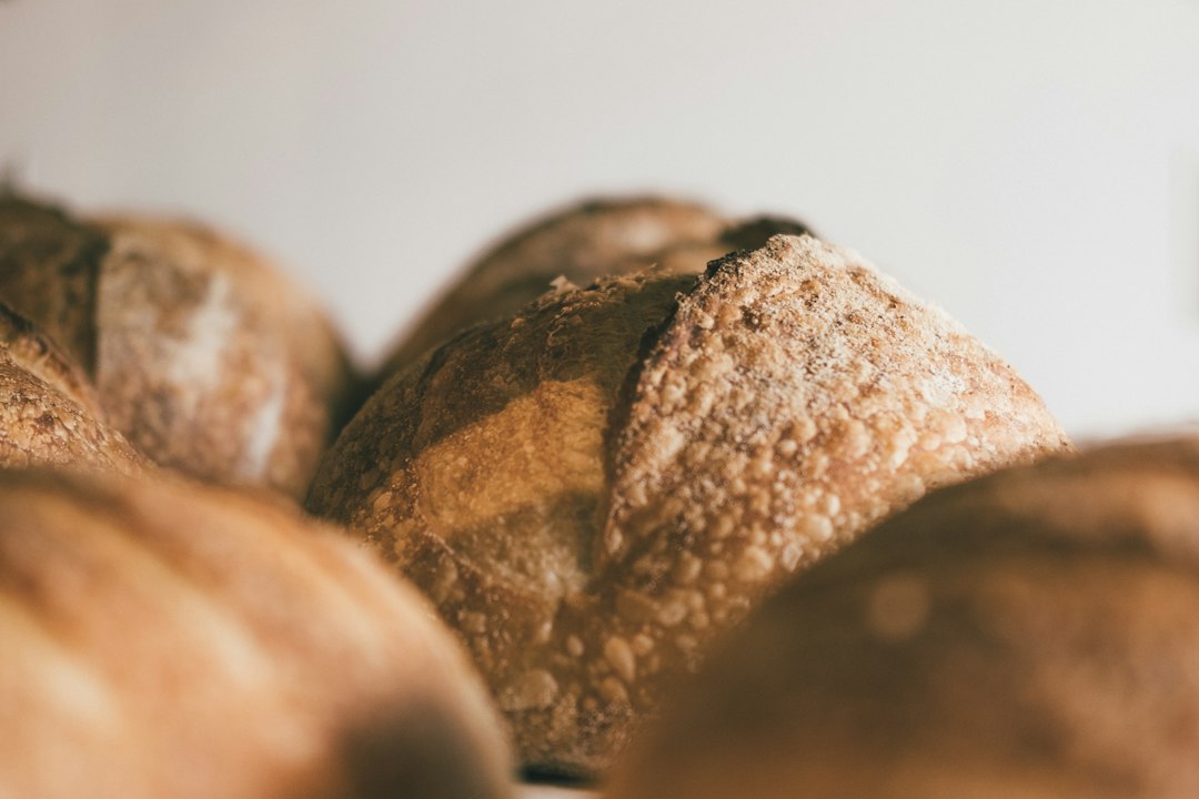 Close-up of round rustic bread loaves with floured, cracked crusts against a soft white background.