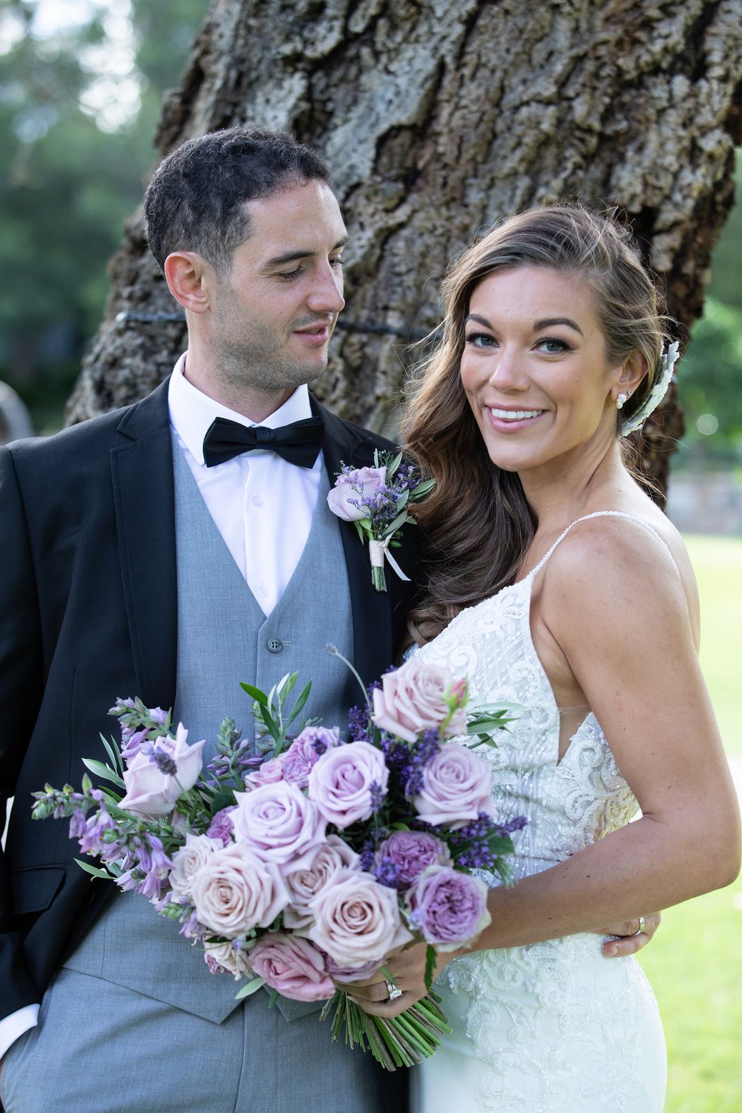 Bride holding a lilac bouquet beside her groom