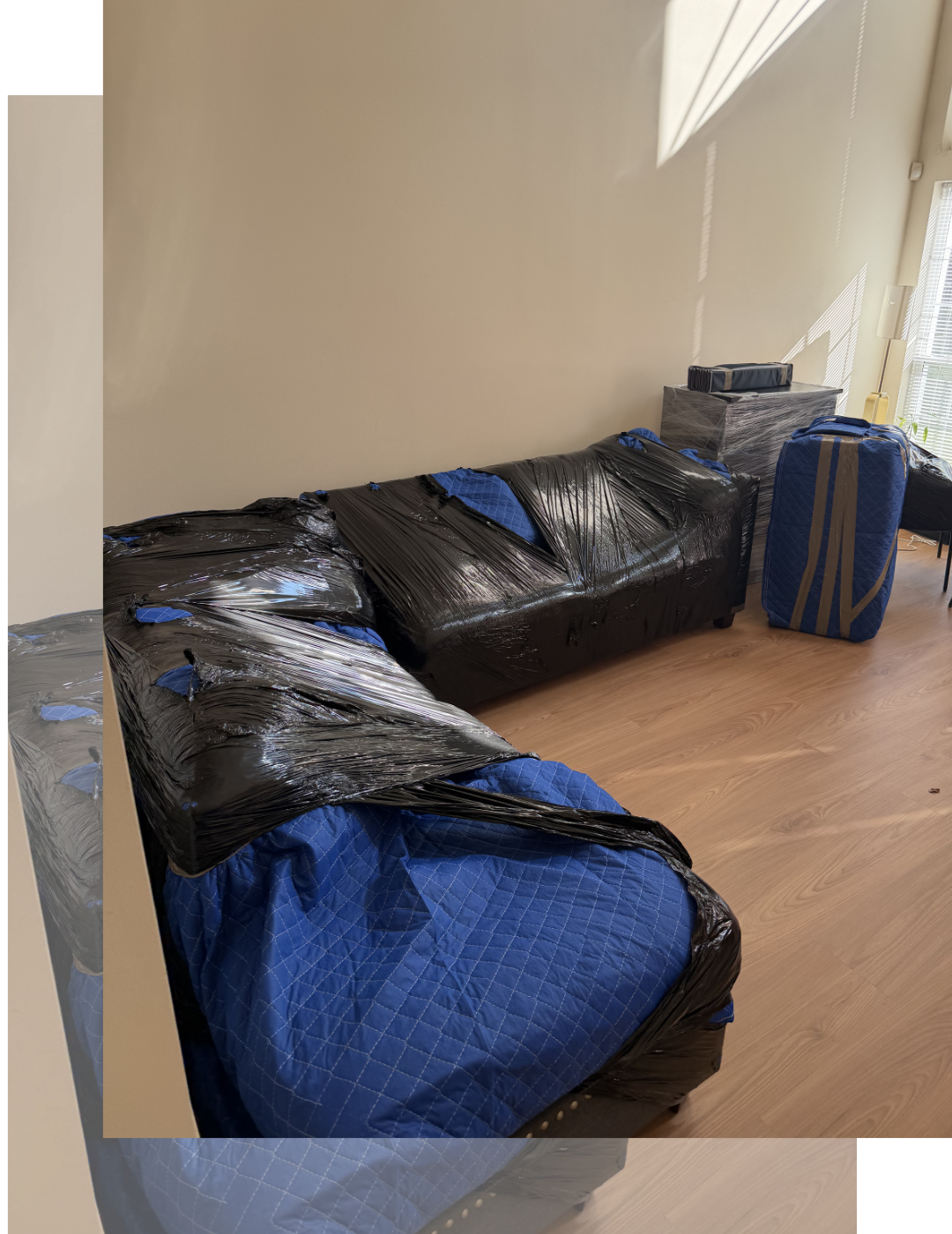 Living room with sectional furniture wrapped in moving blankets and plastic, boxes nearby a fireplace — Keep It Moving Services Burlington County NJ