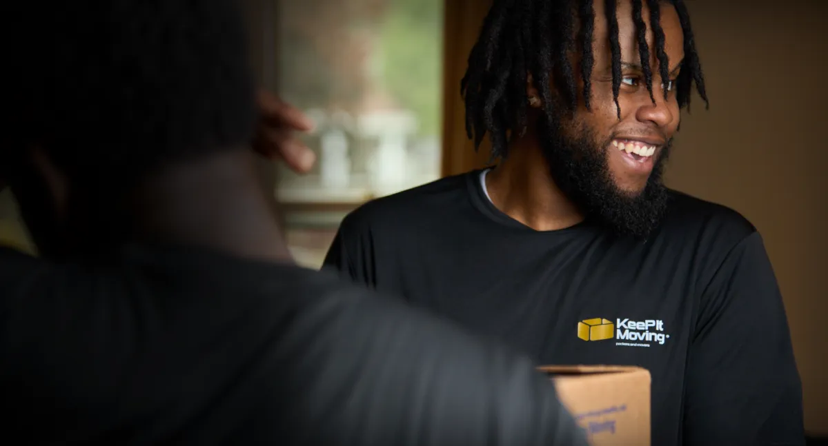 Smiling Keep It Moving Services crew member holding a moving box