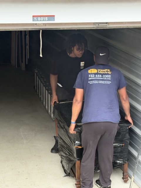 Two Keep It Moving Services crew members loading a storage unit — your NJ moving estimate covers every item