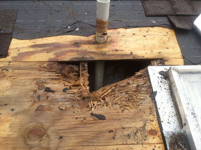 Damaged roof decking showing rotted wood and structural damage requiring roof replacement