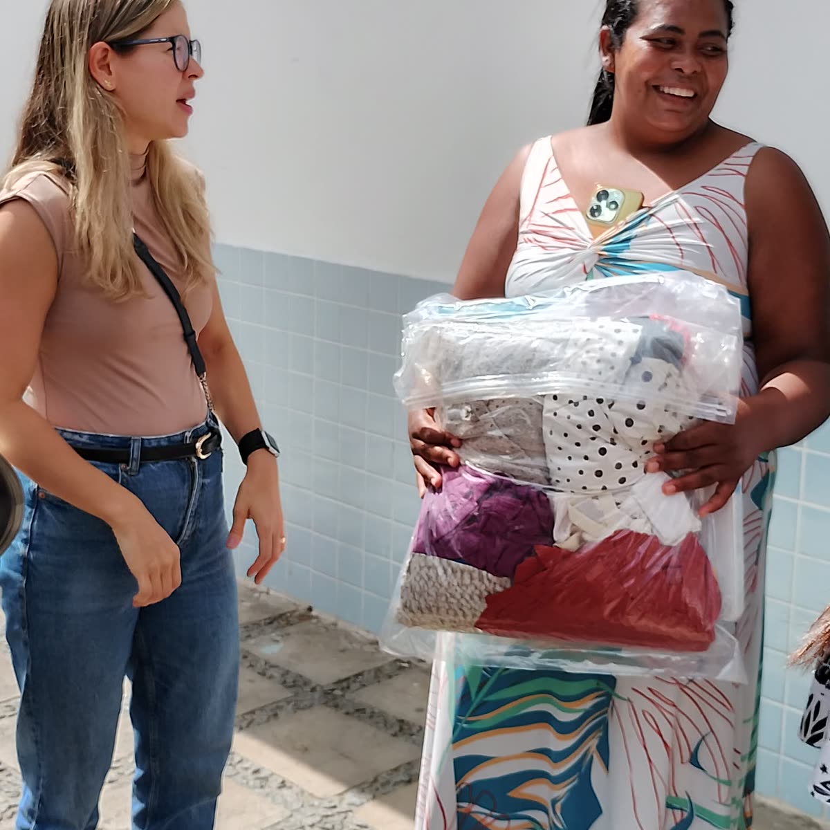 Voluntária entrega enxoval a uma mãe atendida