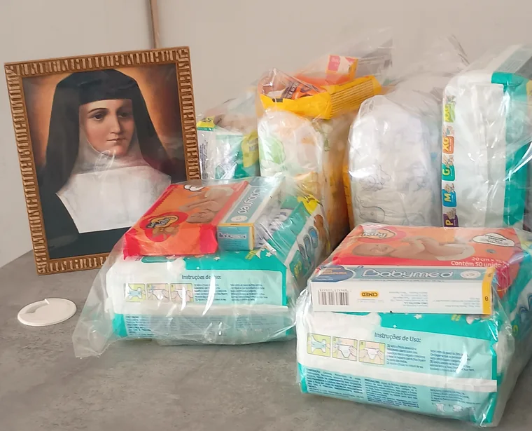 Retrato emoldurado da santa ao lado das doações recebidas pela associação