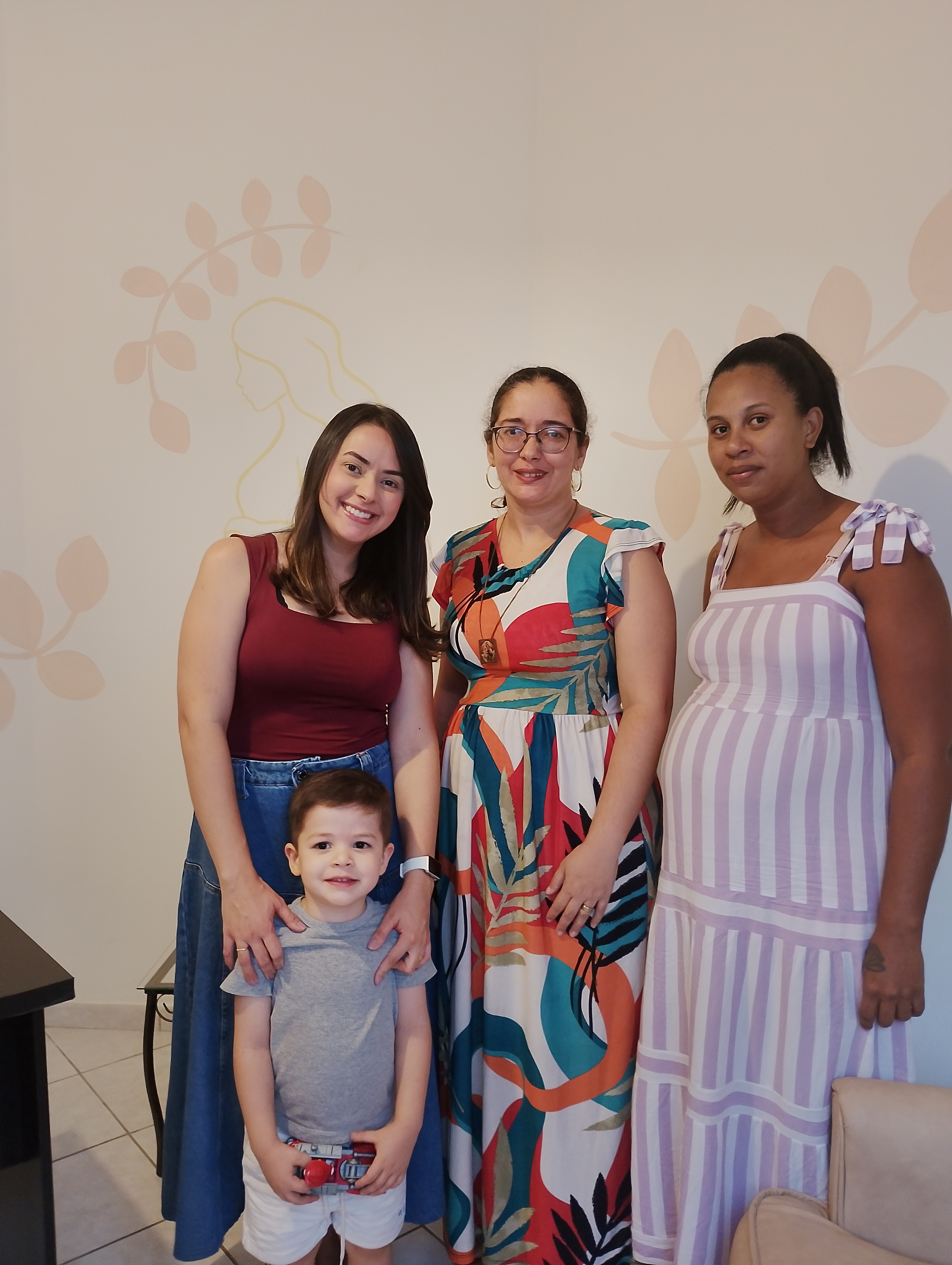 Voluntárias da associação com uma criança e uma gestante acompanhada, na sede