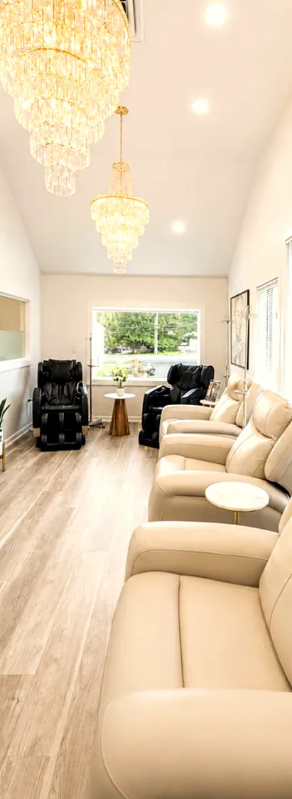 Lounge with cream recliners and chandeliers at JENNVIE Med Spa in Westport, CT