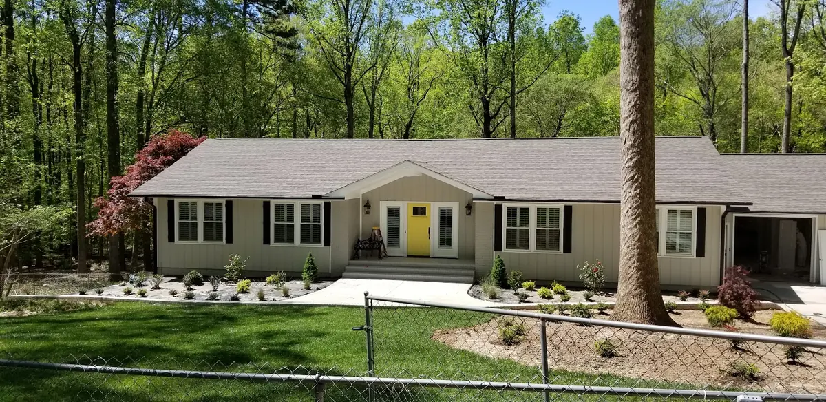 Ranch home with beige siding, black shutters and a bright yellow front door