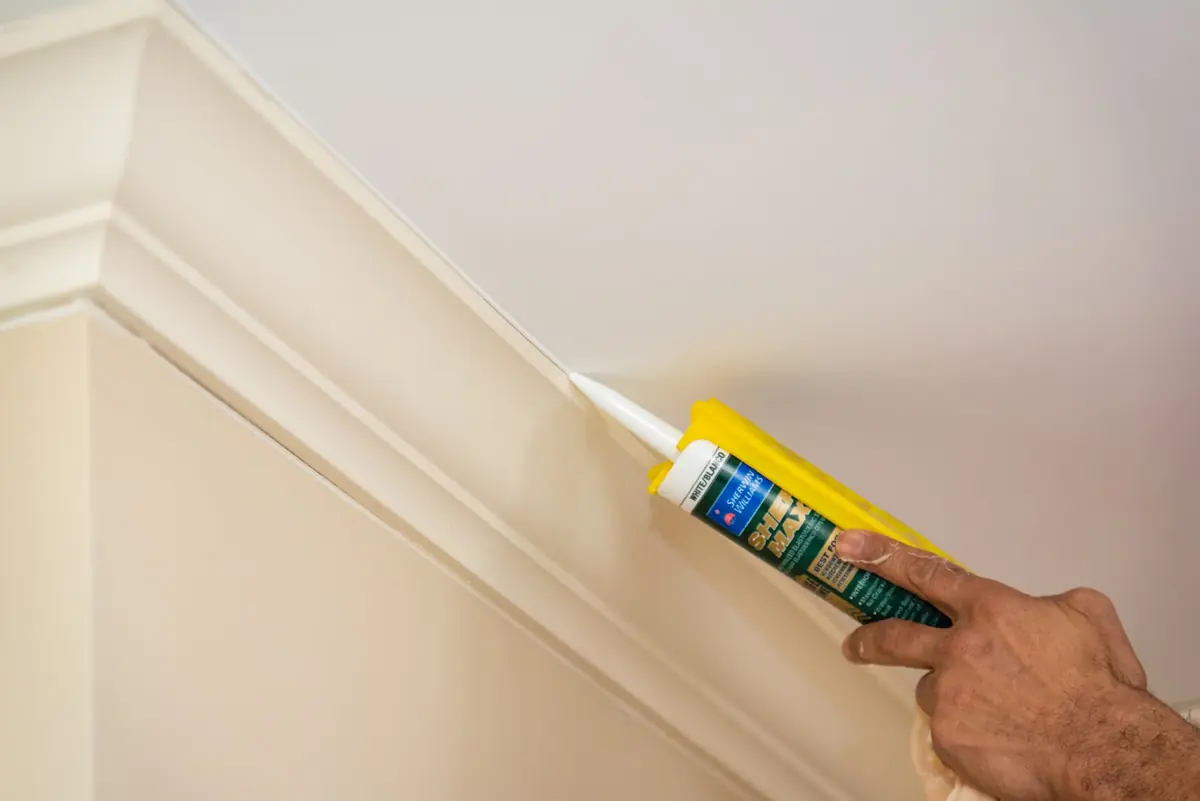 Hand applying a clean bead of caulk to crown molding