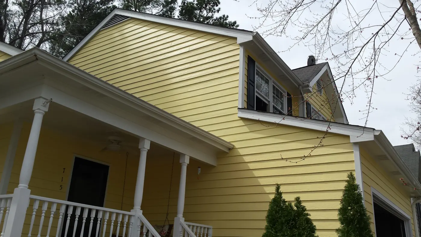 Clean yellow lap siding corner with white trim after repair