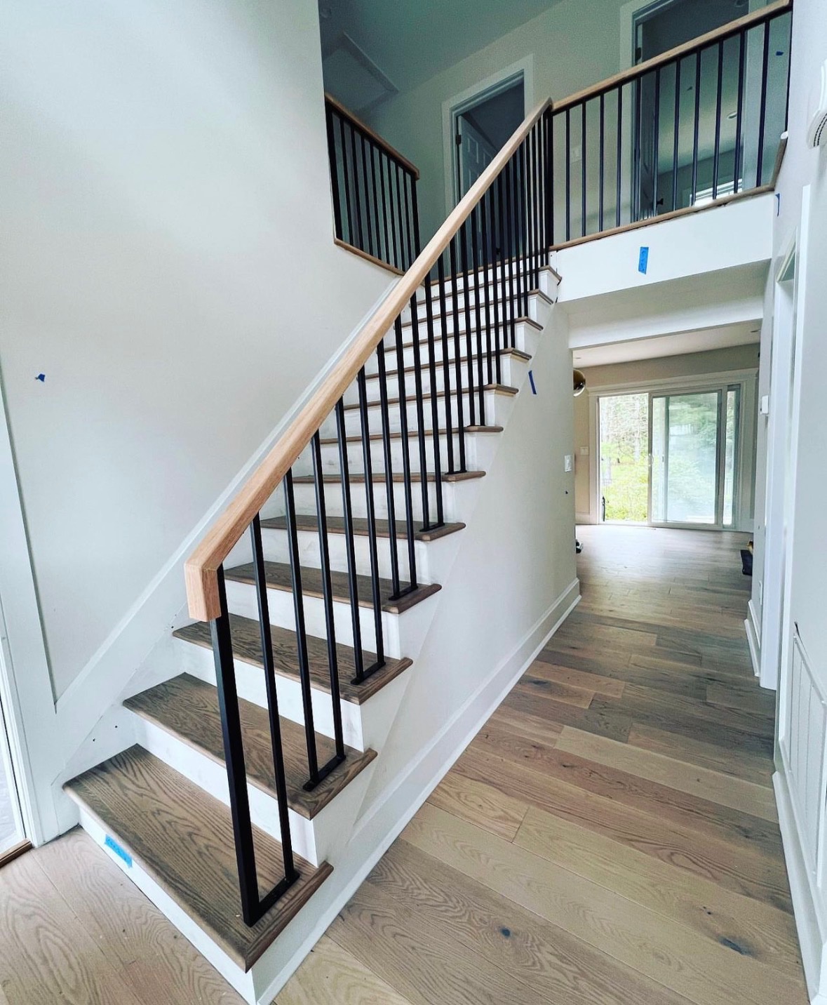Wood handrail with black square baluster staircase in an open concept Poway home