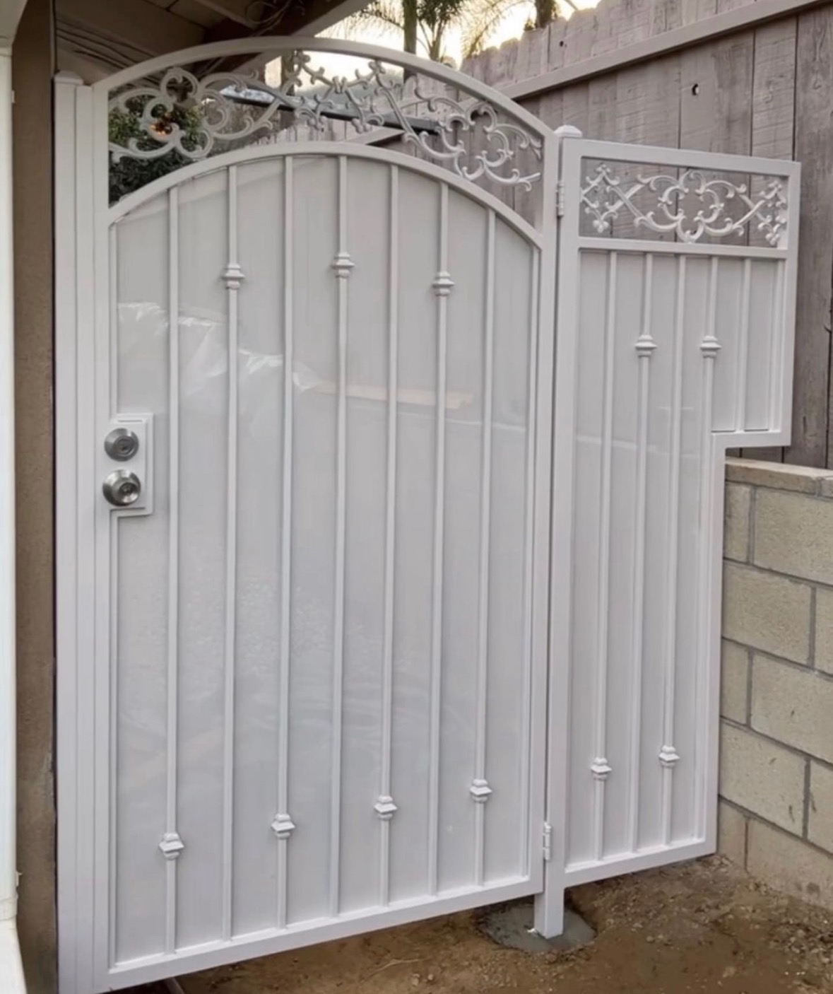 White ornamental arched double gate with decorative scrollwork