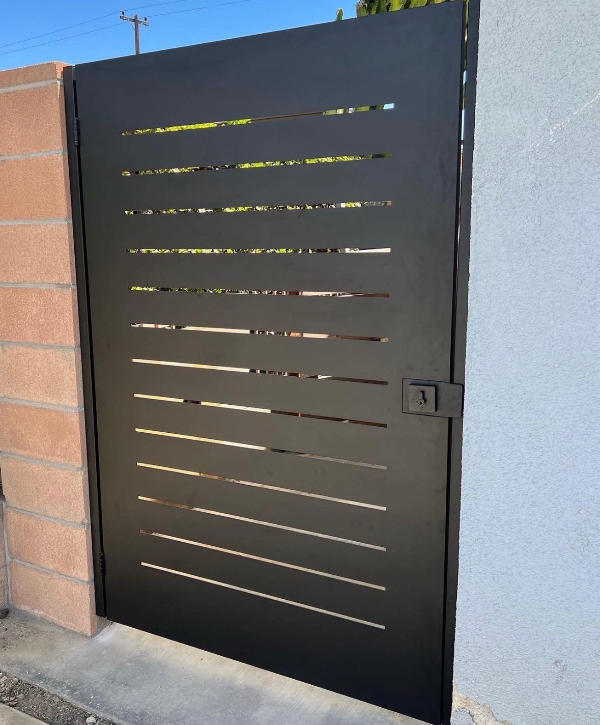 Modern black laser-cut pedestrian gate with a custom commercial design