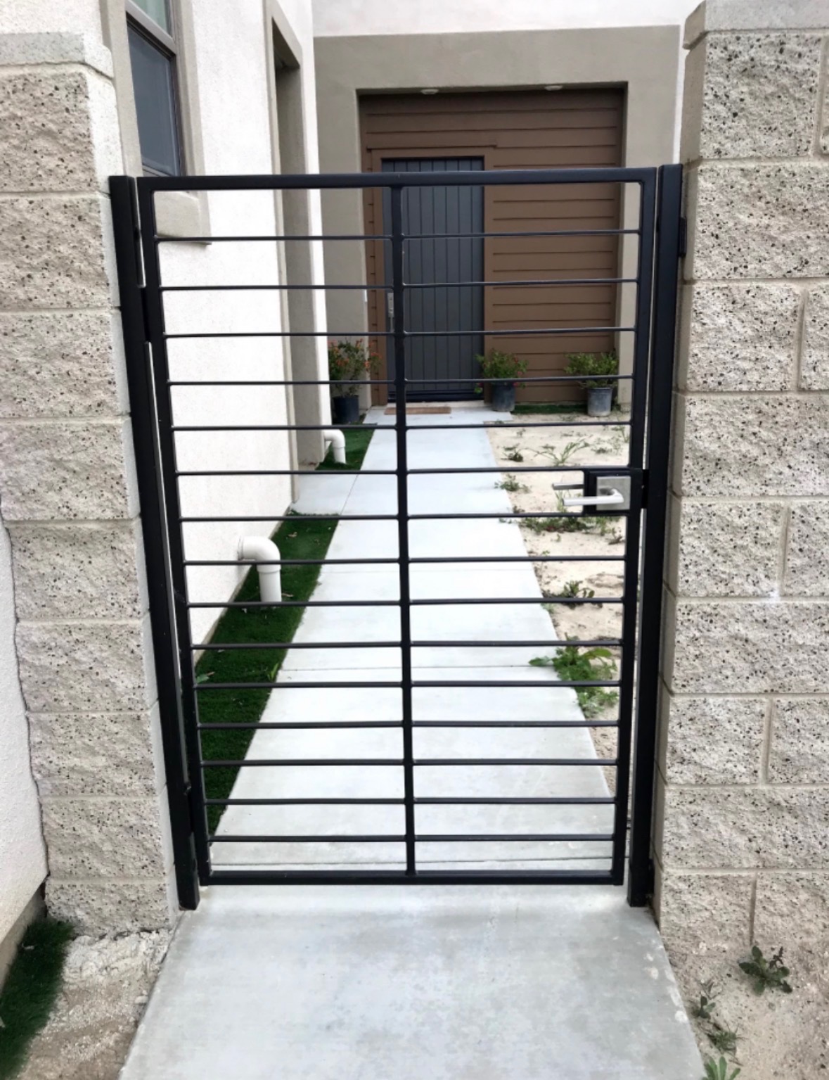 Modern black horizontal pedestrian gate at a commercial concrete block building