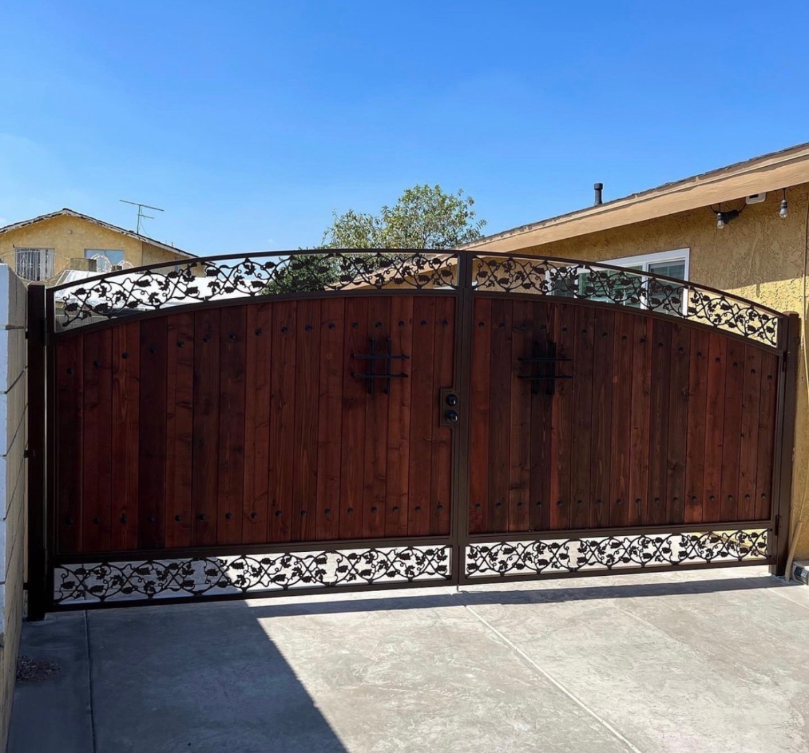 Custom wood and iron driveway gate with grapevine scrollwork design