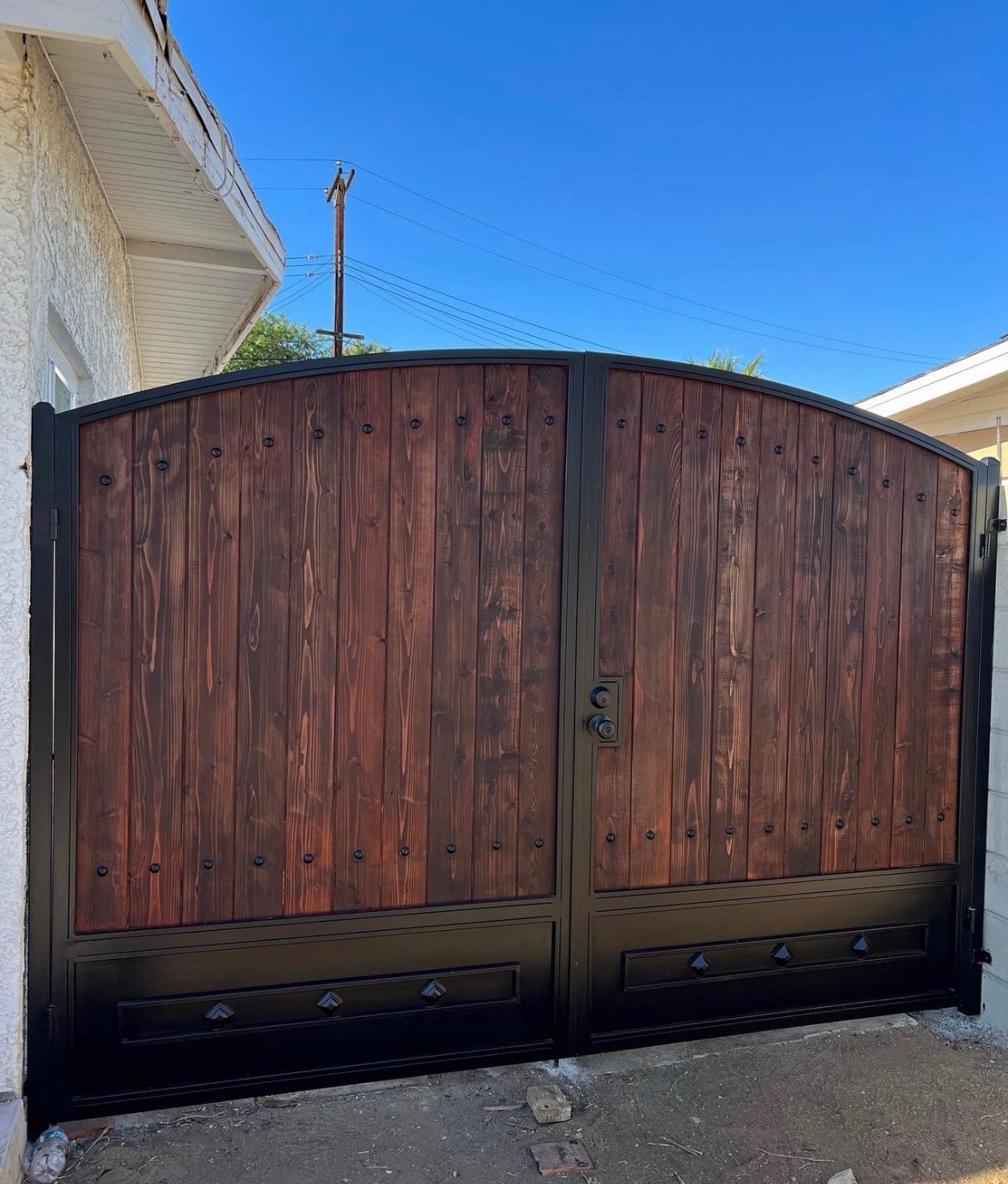 Dark wood and iron arched double driveway gate with diamond accents
