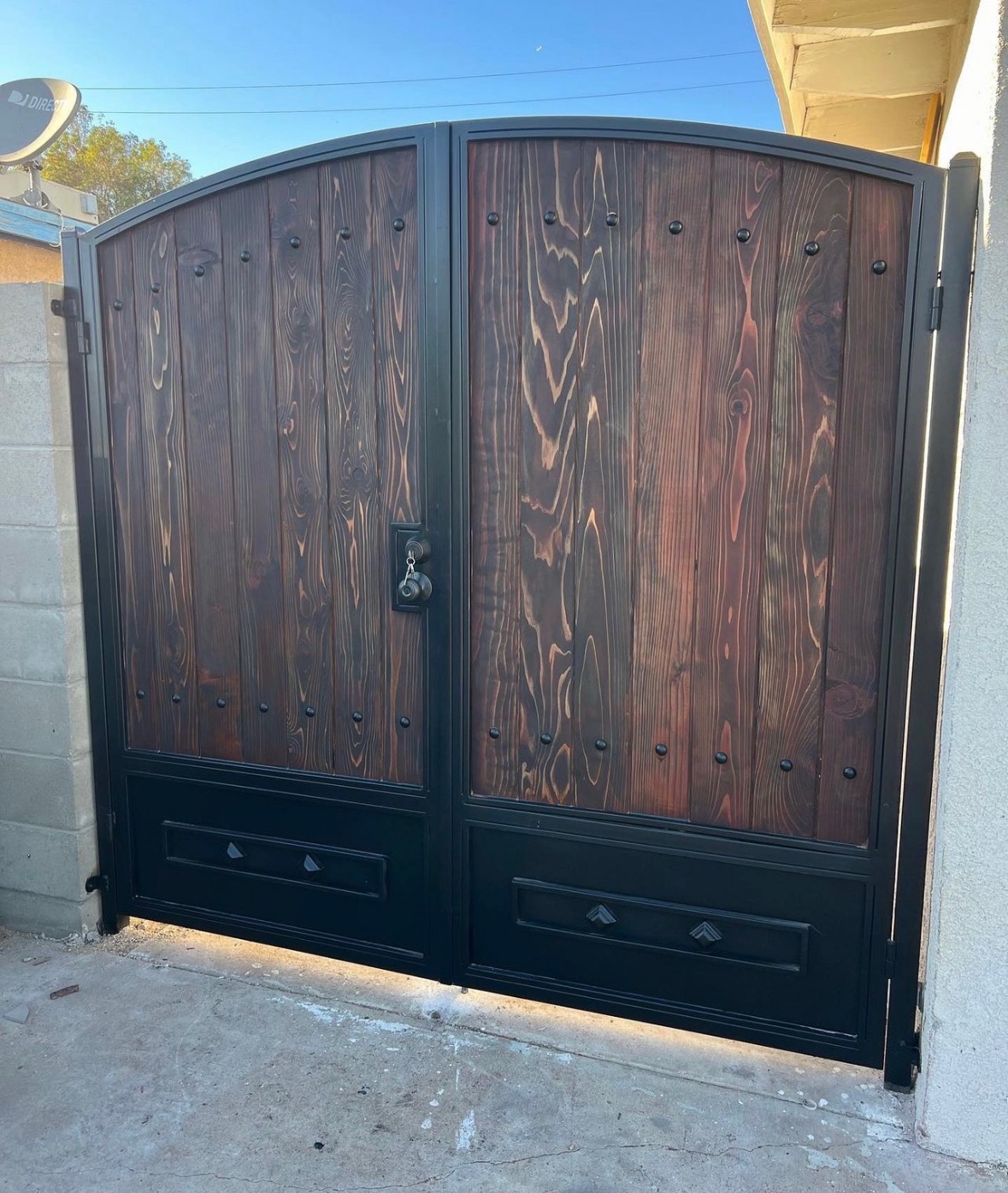 Steel-frame double driveway gate with an arched dark wood finish