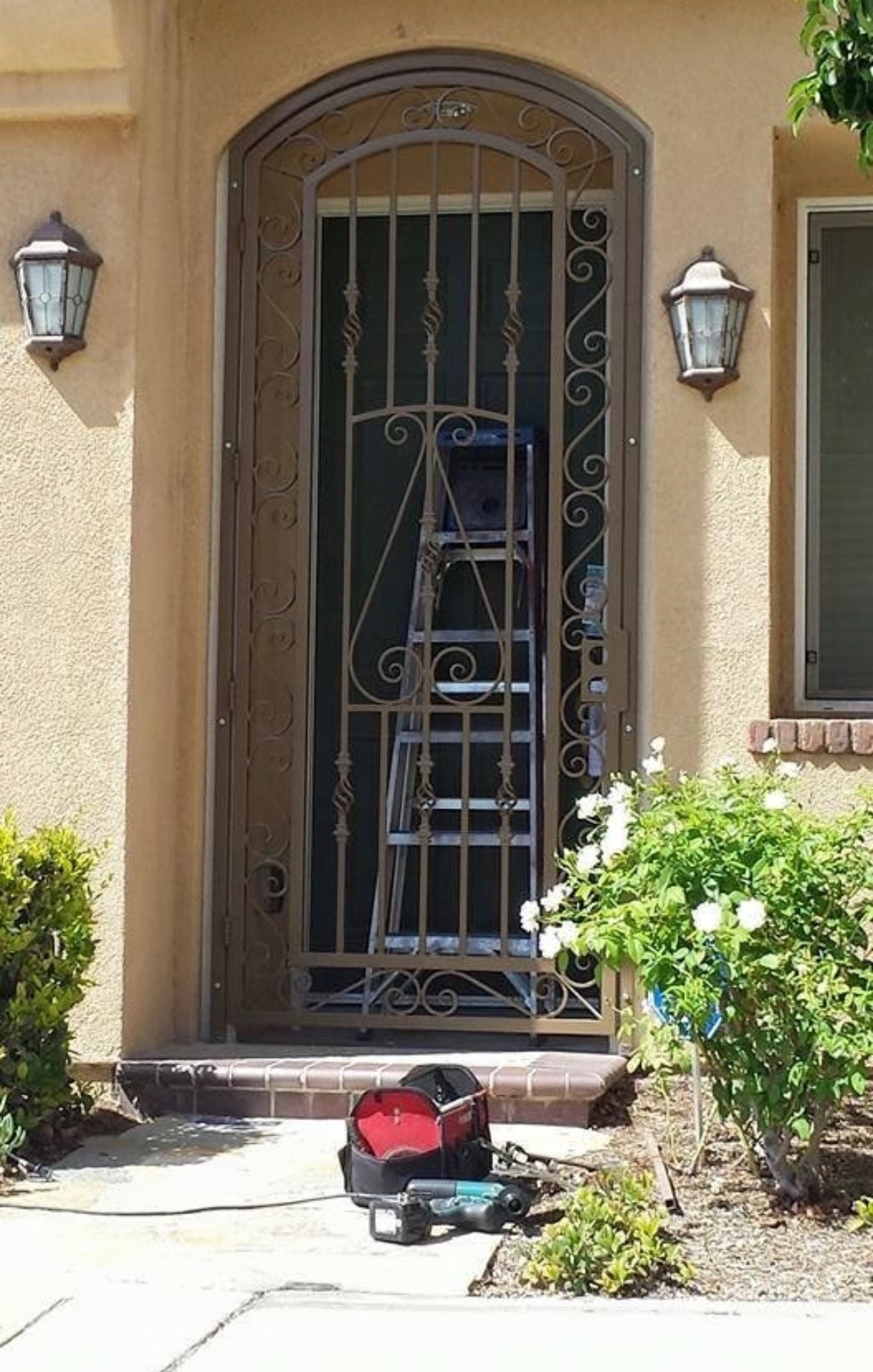 Custom ornamental iron security door with scrollwork, bronze finish installation