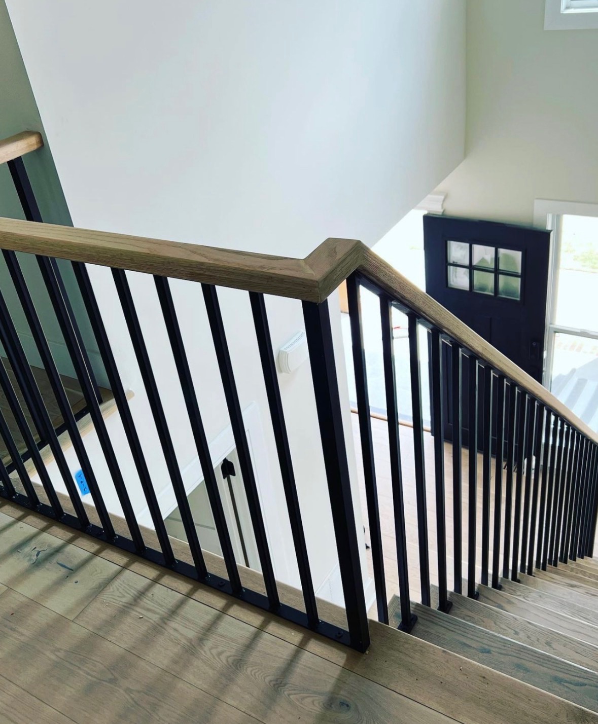 Modern interior stair railing with black iron and wood handrail