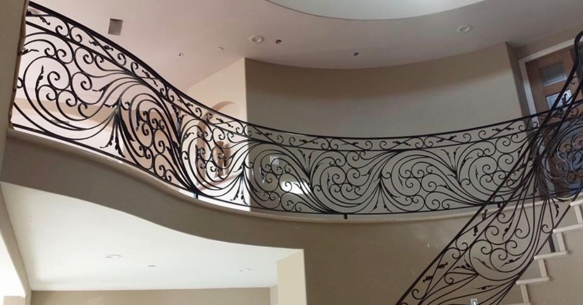 Ornate black wrought iron curved staircase landing railing
