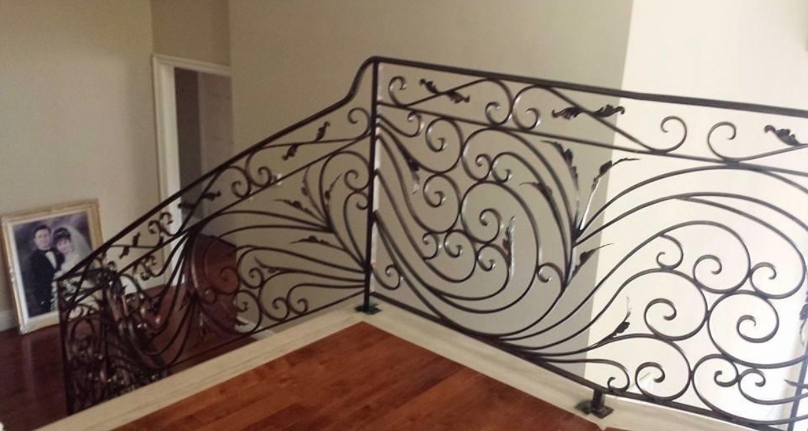 Ornate black wrought iron staircase railing with scroll detail at the corner