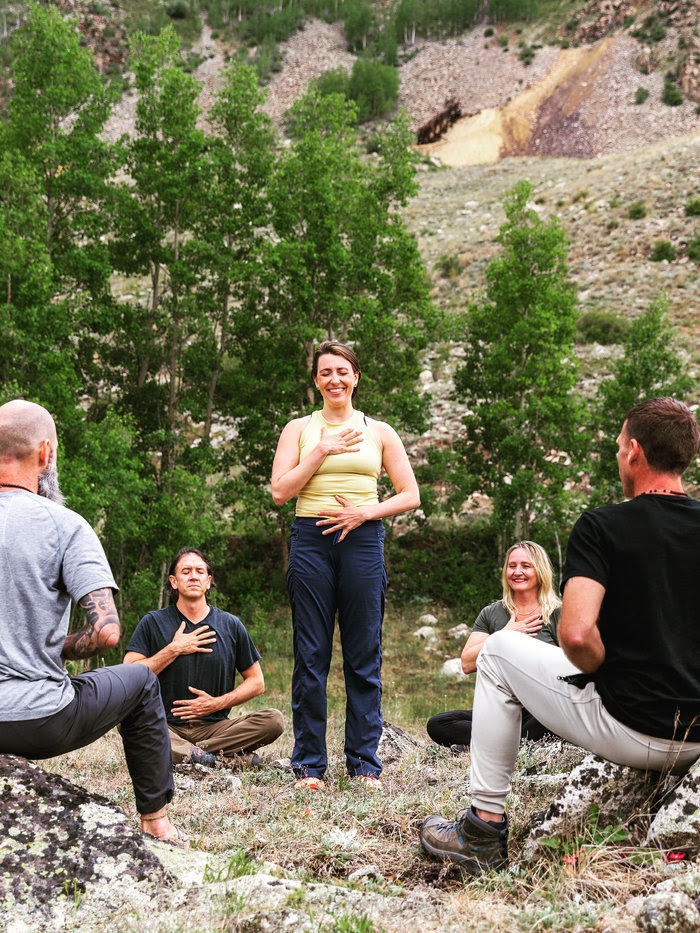 A group breathwork session held outdoors in a mountain setting
