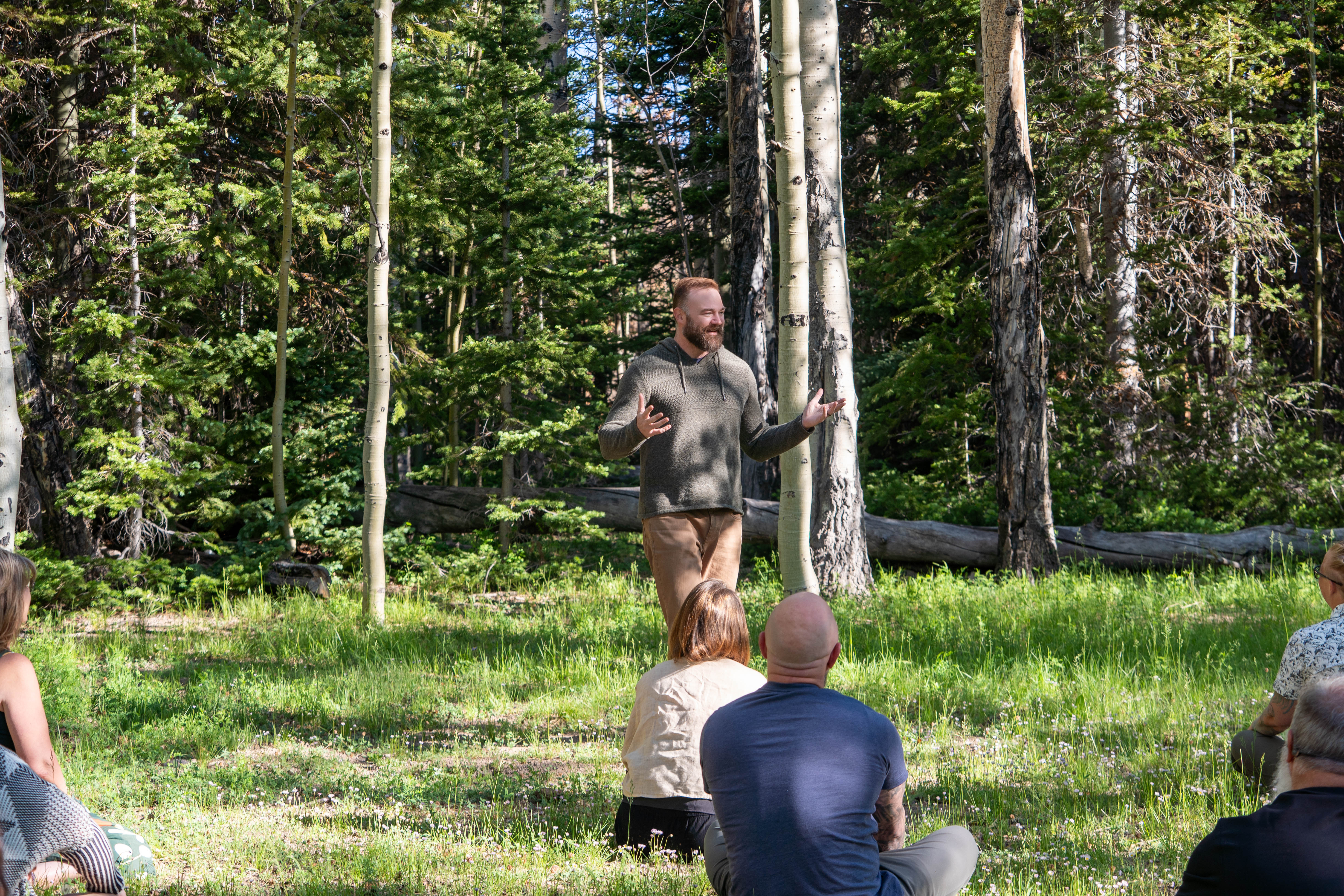 Faculty teaching a seated cohort in an aspen grove during the Language of Breath capstone