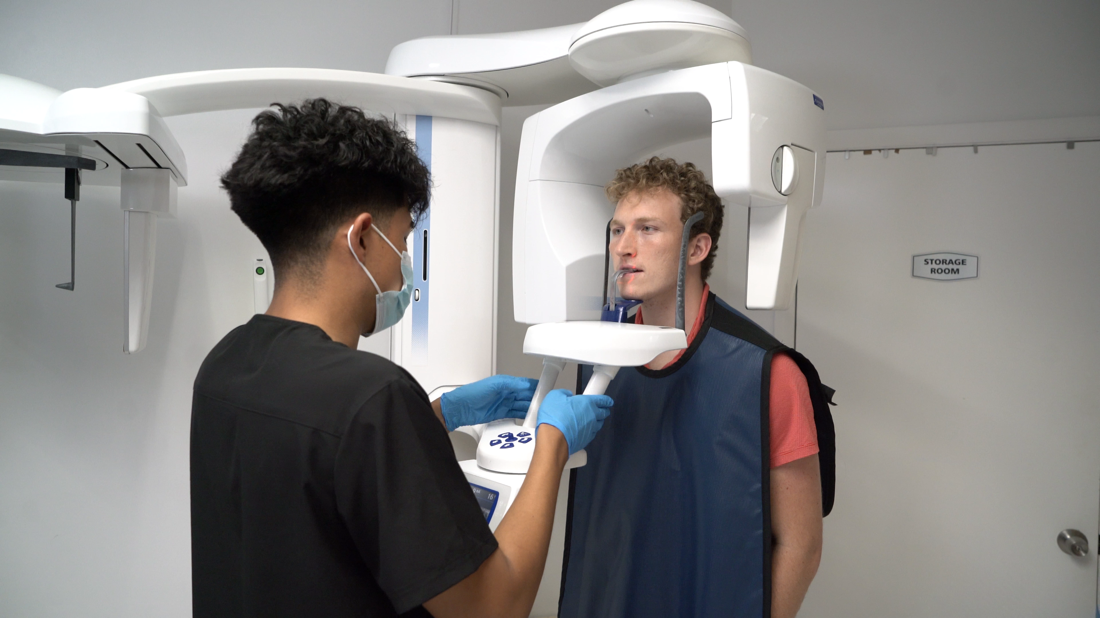 A student practices positioning at dental radiography equipment.