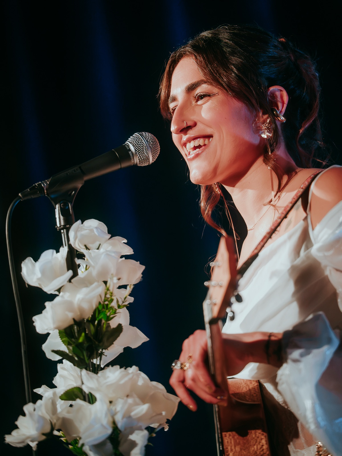 FÏO sonriendo frente al micrófono con flores blancas