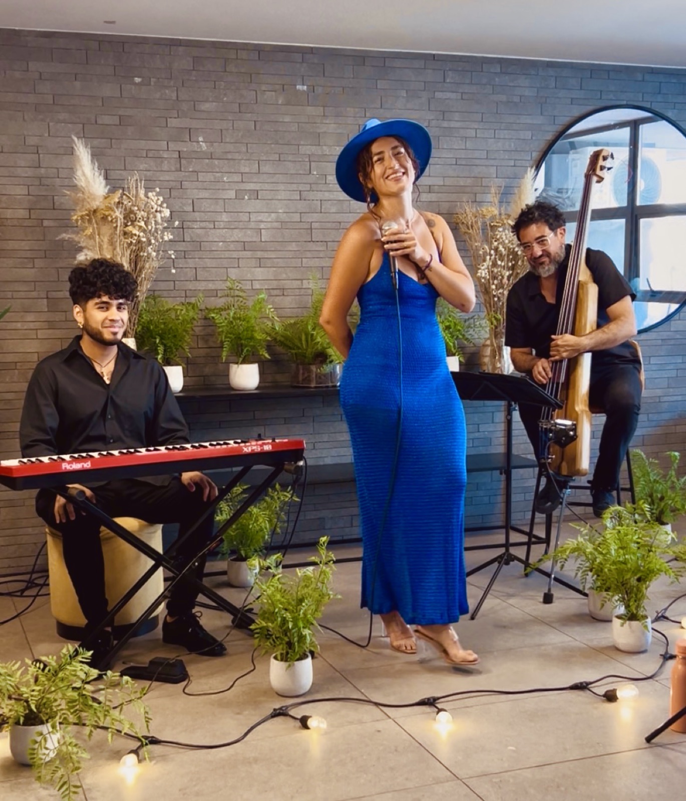 Fiorella de vestido azul con su trío en un evento